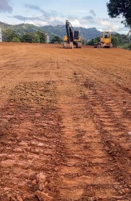 An excavator and a bulldozer sit on a large, cleared dirt lot with distant hills — BO. QUEBRADA NEGRITO, TRUJILLO ALTO, PR