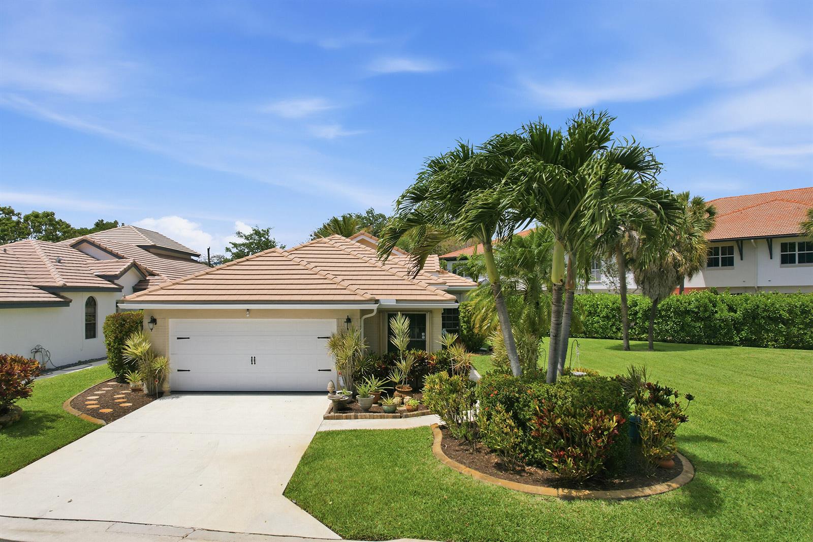 A single-story house with a tan tile roof, white garage door, and a palm tree garden — 262 Sherwood Forest Drive, Delray Beach FL 33445, DELRAY BEACH, FL