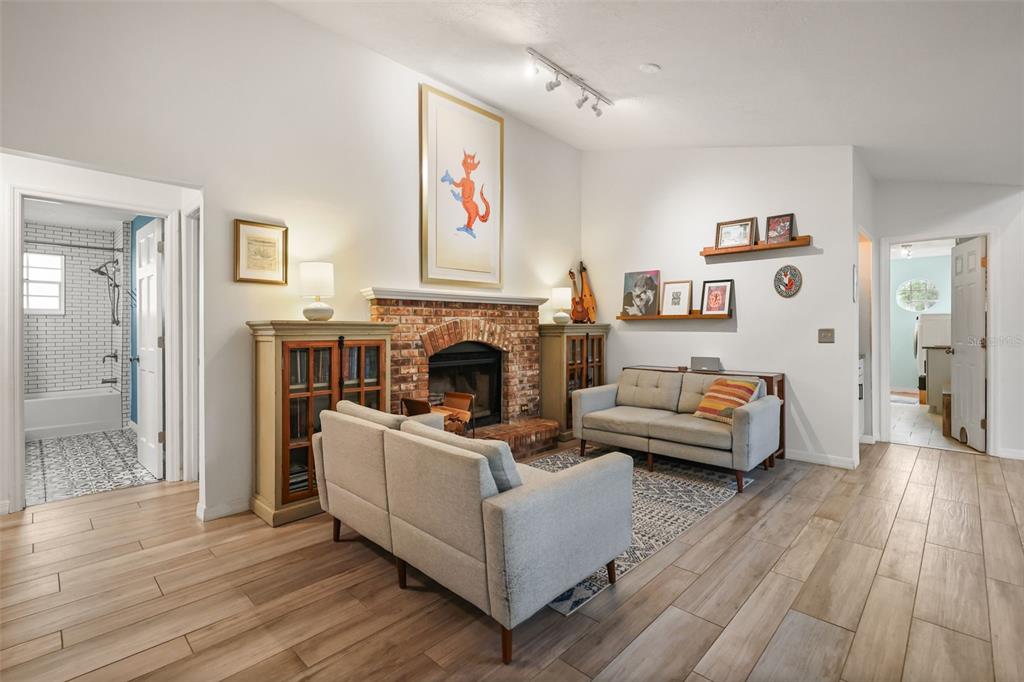 A living room features a brick fireplace, two grey sofas, and light wood-look flooring — 2504 ORCHARD DRIVE, APOPKA, FL