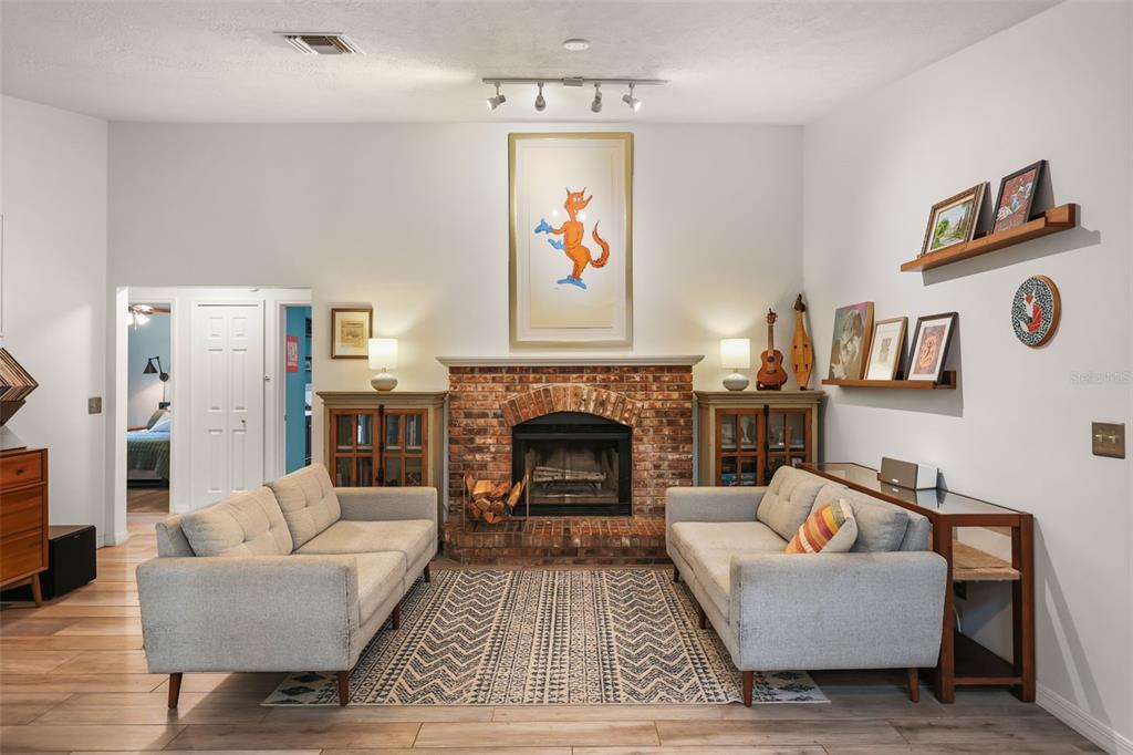 A living room features a brick fireplace, two grey sofas, and a patterned area rug — 2504 ORCHARD DRIVE, APOPKA, FL