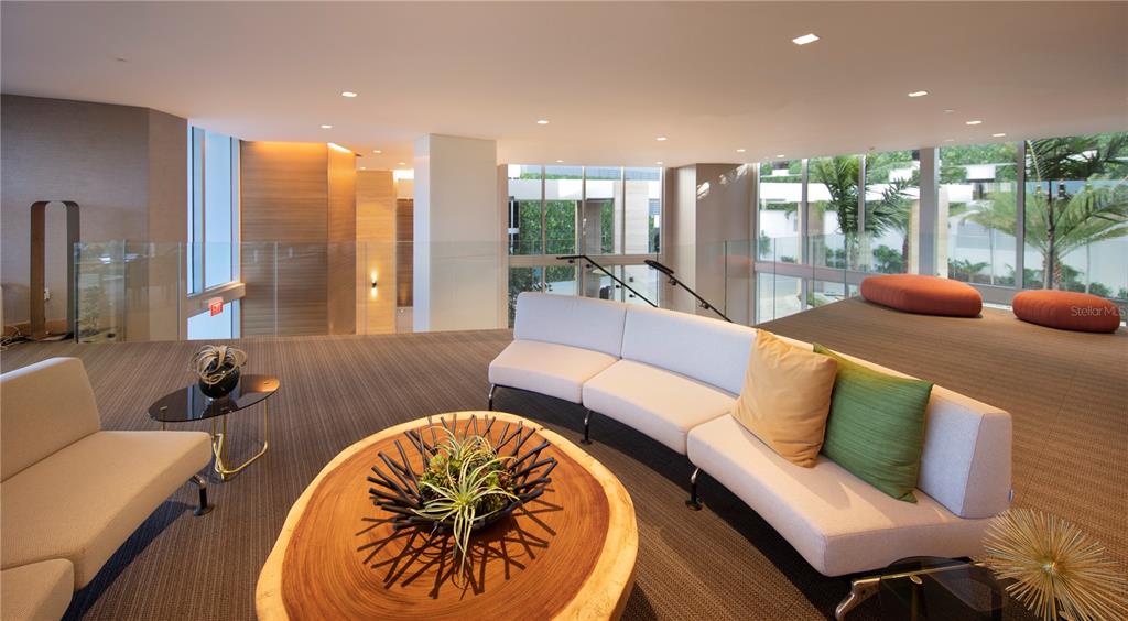 A modern lounge area features a curved sofa, a live-edge wood coffee table, and floor-to-ceiling windows — 16385 BISCAYNE BOULEVARD UNIT 305, NORTH MIAMI BEACH, FL