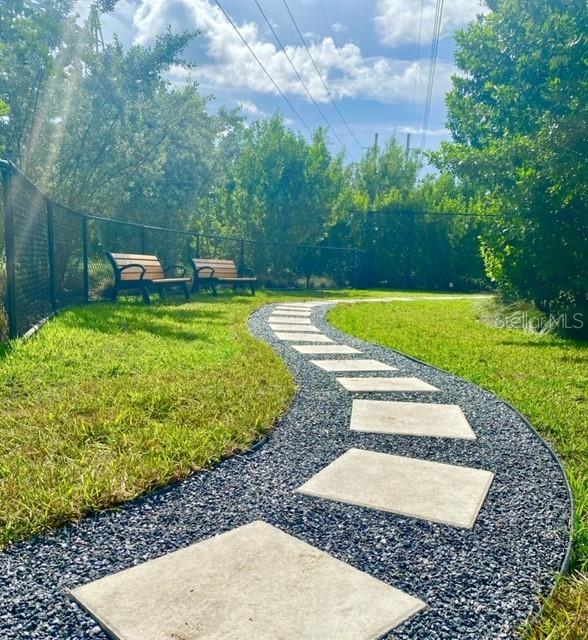 A winding stone paver path leads through a grassy yard with two benches near a fence — 16385 BISCAYNE BOULEVARD UNIT 305, NORTH MIAMI BEACH, FL
