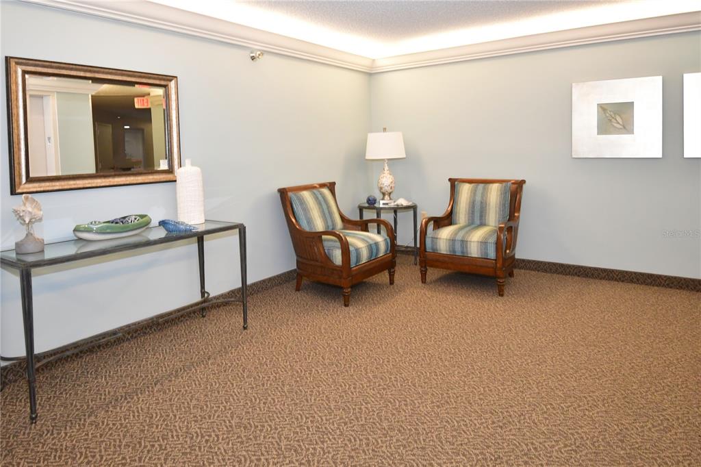 A seating area features two striped armchairs, a side table with a lamp, and console — 690 ISLAND WAY UNIT 208, CLEARWATER, FL