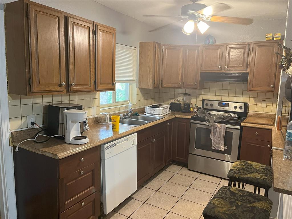 A kitchen with wood cabinets, laminate countertops, stainless steel appliances, and light-colored tile flooring — 120 S SAN REMO AVENUE, CLEARWATER, FL