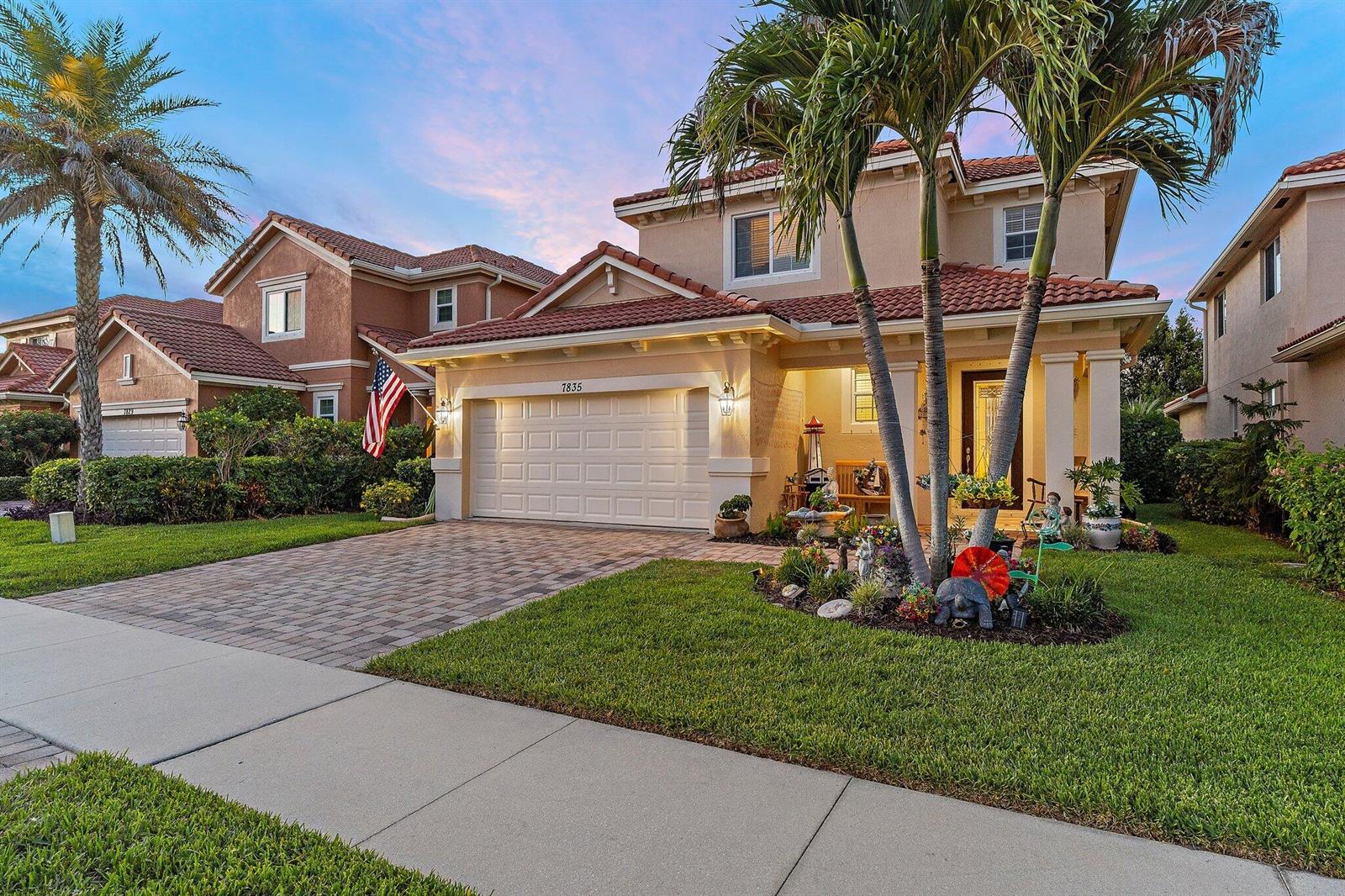 A two-story suburban house features a tiled roof, a paved driveway, and palm trees — 7835 SE Heritage Boulevard, Hobe Sound FL 33455, HOBE SOUND, FL