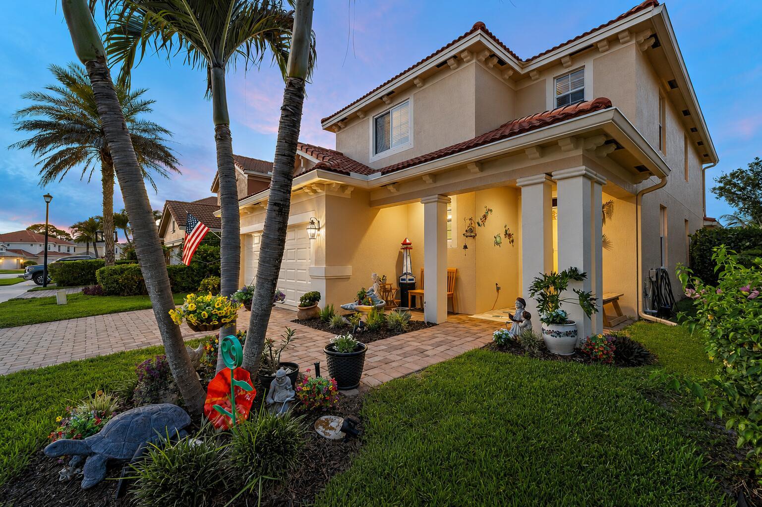 A two-story beige house with a tiled roof, palm trees, and a paved walkway — 7835 SE Heritage Boulevard, Hobe Sound FL 33455, HOBE SOUND, FL