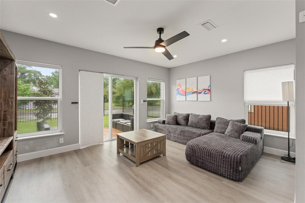 A living room with light wood floors, a gray sectional sofa, and a sliding glass door — 2951 KINGS ROAD, SANFORD, FL