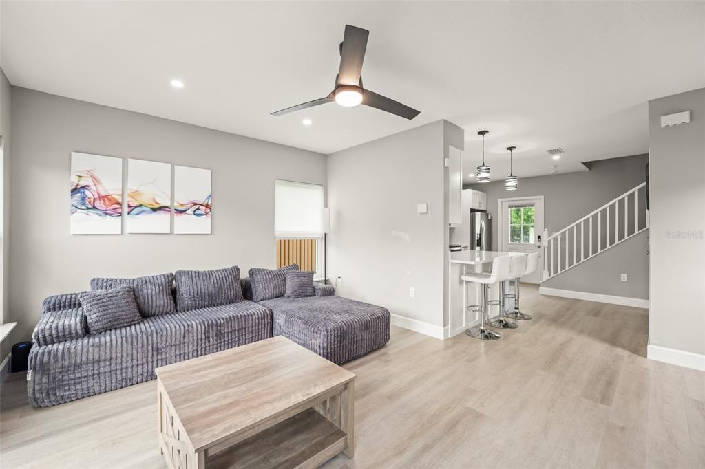 A living room with a grey sectional sofa, wood coffee table, and an adjacent kitchen — 2951 KINGS ROAD, SANFORD, FL