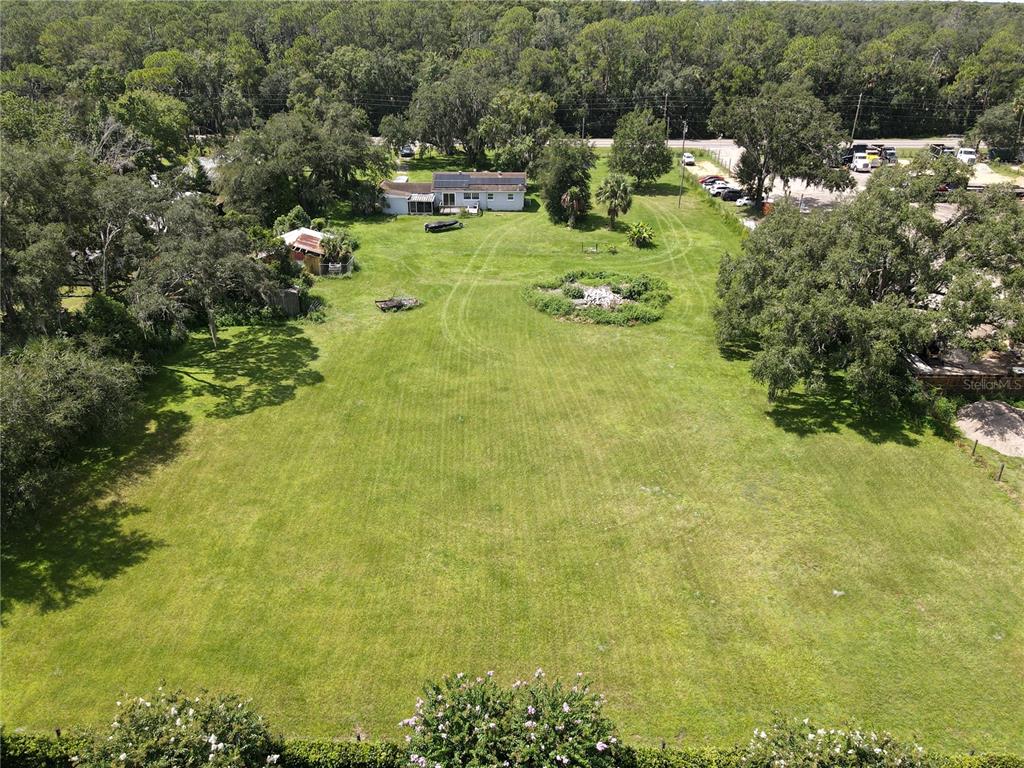 An aerial view shows a large grassy lot with a house, outbuildings, and surrounding trees — 6043 S ORANGE BLOSSOM TRAIL, DAVENPORT, FL