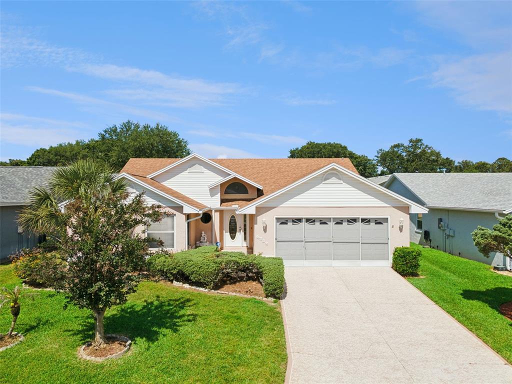 A single-story suburban house with a tan stucco exterior, brown shingle roof, and palm tree — 6232 EGRET DRIVE, LAKELAND, FL