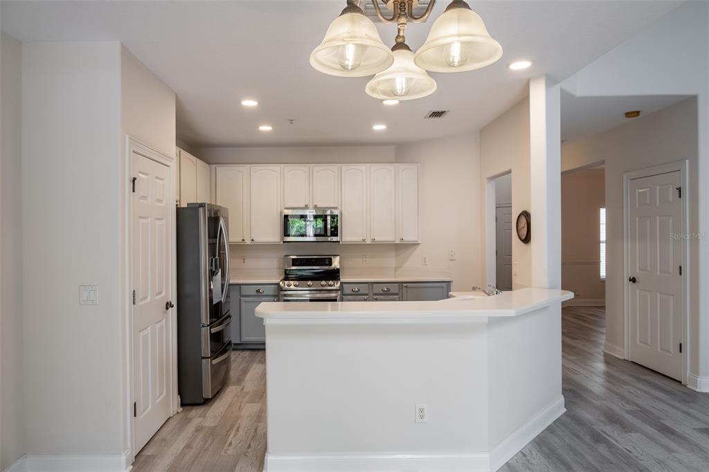 A kitchen features white upper cabinets, gray lower cabinets, stainless steel appliances, and a breakfast bar — 6959 SORRENTO STREET, ORLANDO, FL