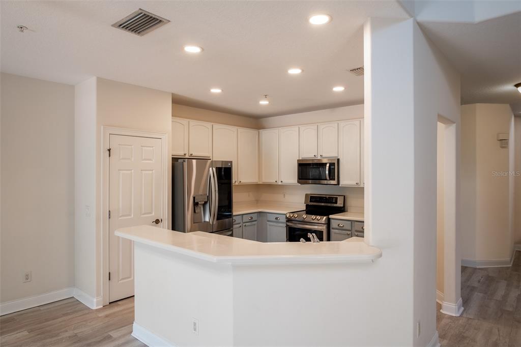 A kitchen features white upper cabinets, gray lower cabinets, stainless steel appliances, and a breakfast bar — 6959 SORRENTO STREET, ORLANDO, FL