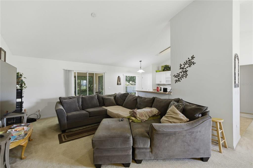 A living room features a large gray sectional sofa, carpeted floors, and an open kitchen — 3959 SW 129TH STREET, OCALA, FL