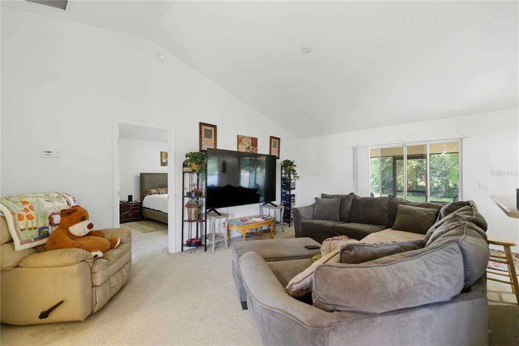 A living room with a vaulted ceiling, gray sectional sofa, television, and a beige recliner — 3959 SW 129TH STREET, OCALA, FL