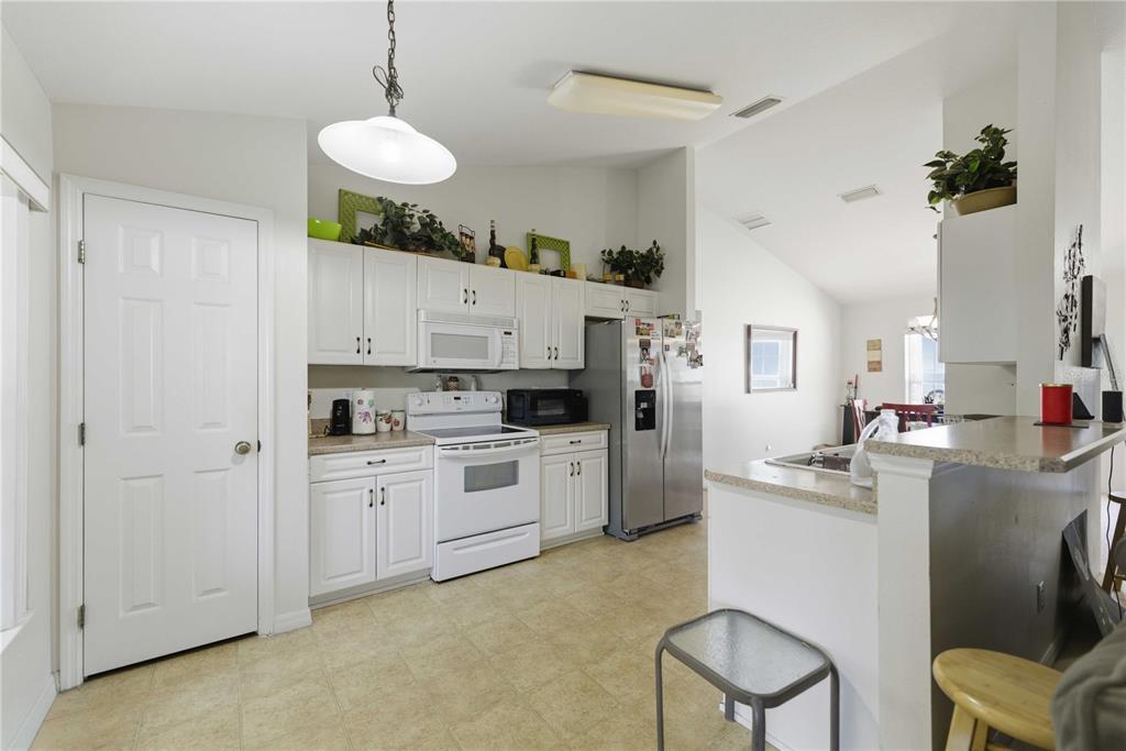 A kitchen with white cabinets, stainless steel appliances, and a breakfast bar — 3959 SW 129TH STREET, OCALA, FL