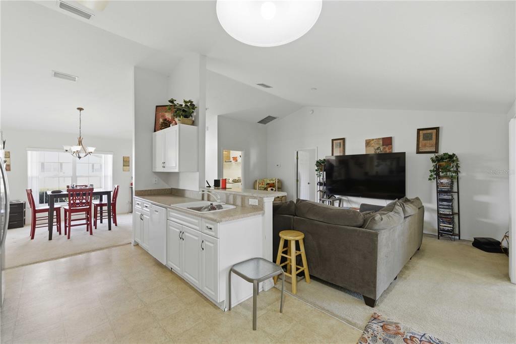 A kitchen with white cabinets and a sink overlooks a living room with a sofa — 3959 SW 129TH STREET, OCALA, FL