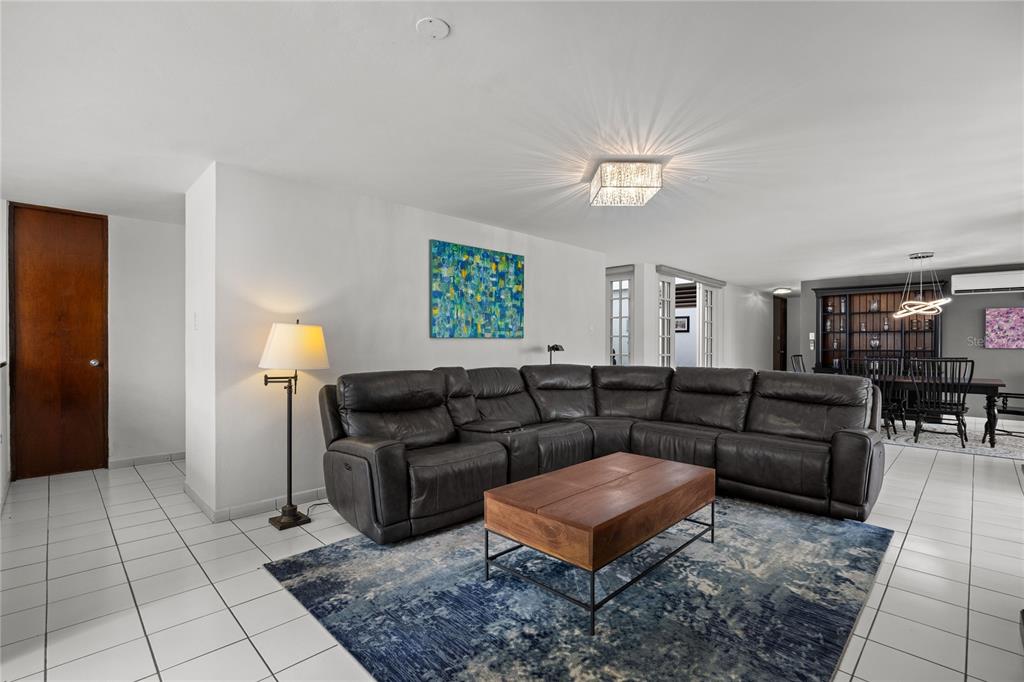 A living room features a dark leather sectional, a wooden coffee table, and tile flooring — B-31 Poppy Street PARQUE FORESTAL, SAN JUAN, PR