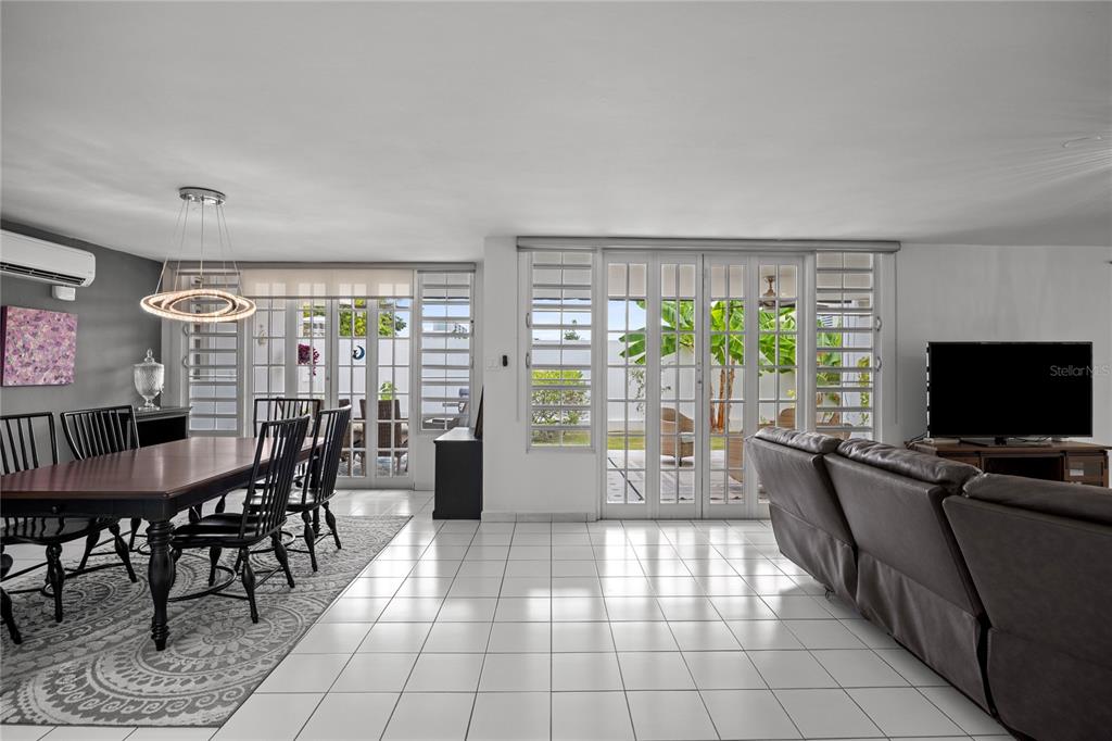 A dining area and living room with white tile floors, large windows, and patio doors — B-31 Poppy Street PARQUE FORESTAL, SAN JUAN, PR