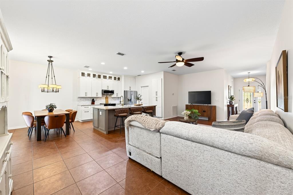 An open-concept kitchen, dining area, and living room with tile floors and white cabinetry — 233 W FIESTA KEY LOOP, DELAND, FL