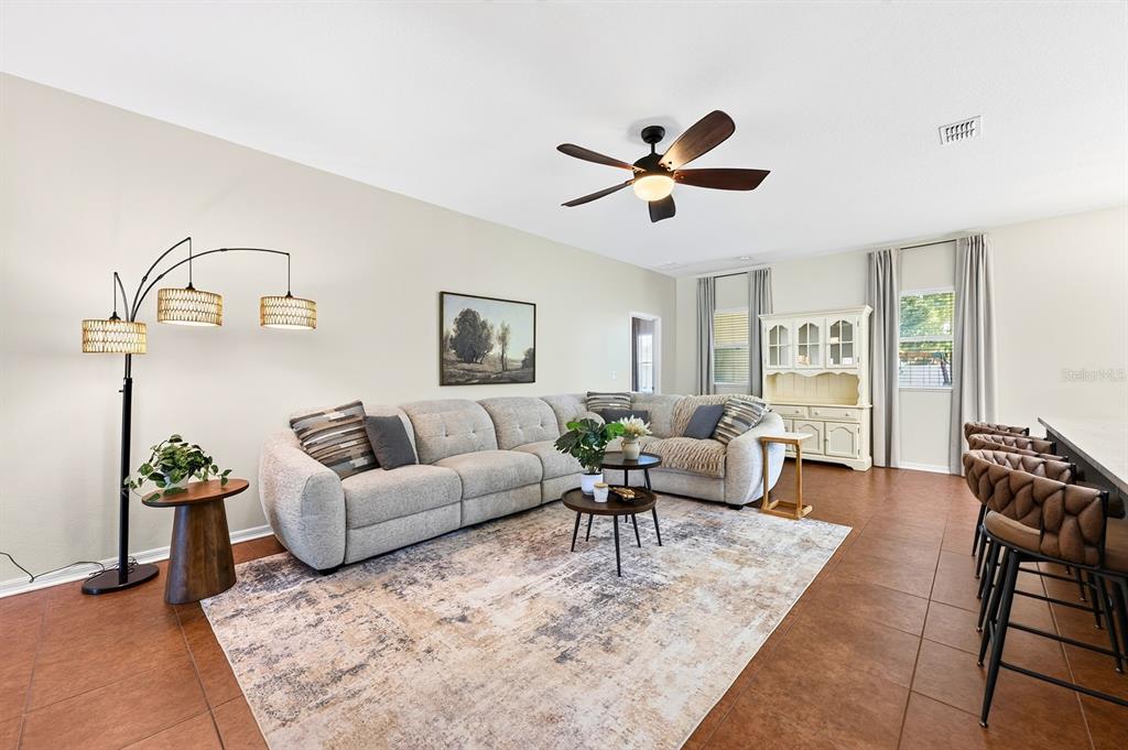 A living room features a large sectional sofa, a patterned area rug, and tile flooring — 233 W FIESTA KEY LOOP, DELAND, FL