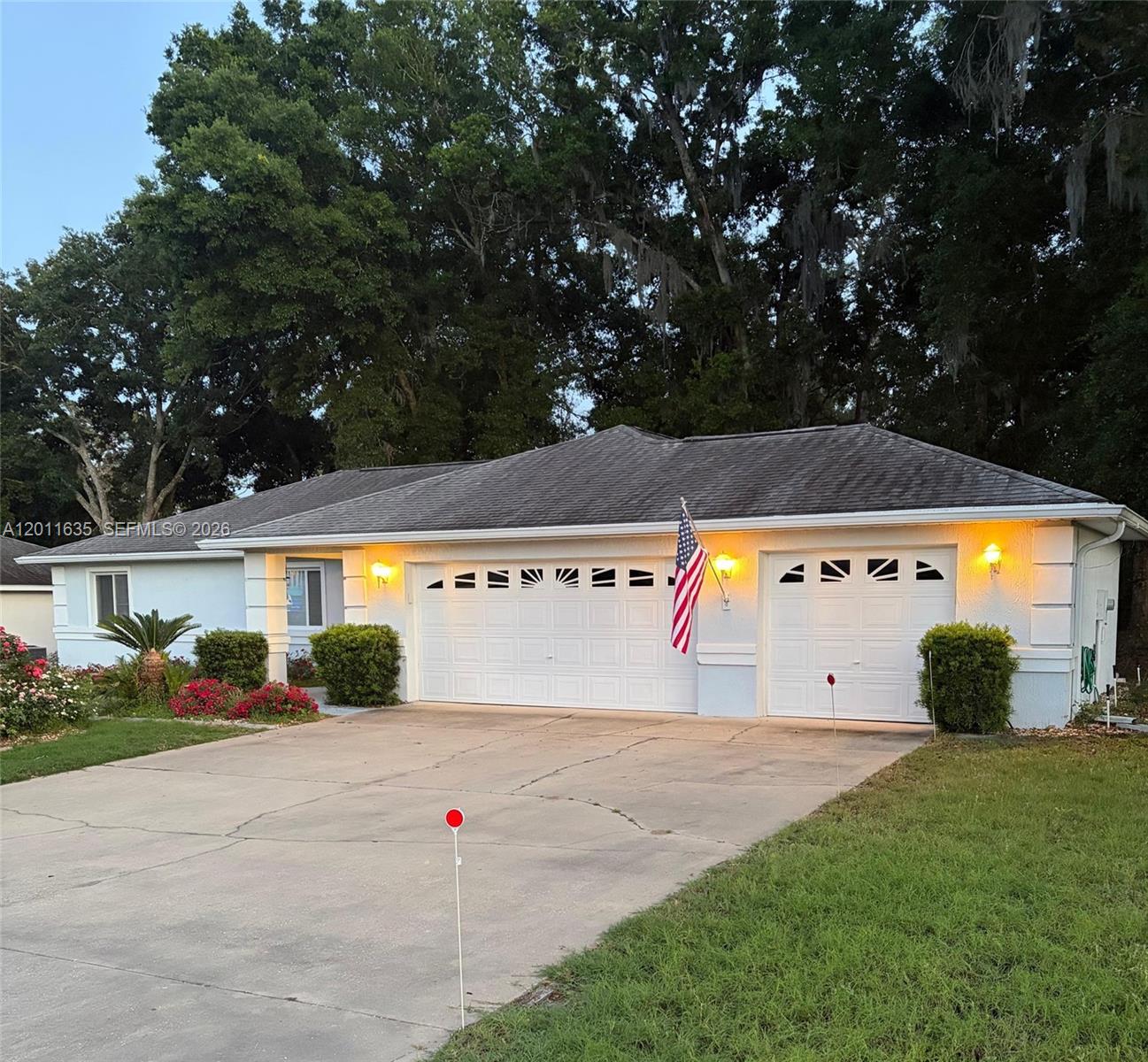 A single-story house with a white stucco exterior, a three-car garage, and a concrete driveway — 6064 SW 103RD LOOP, Ocala FL 34476, OCALA, FL