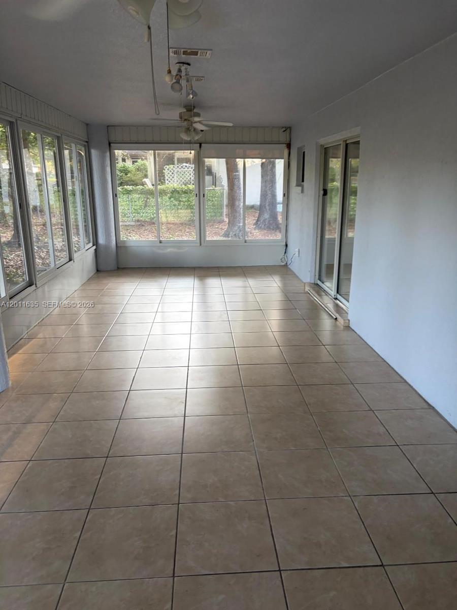 A sunroom features light-colored tile flooring, large windows, and two ceiling fans — 6064 SW 103RD LOOP, Ocala FL 34476, OCALA, FL