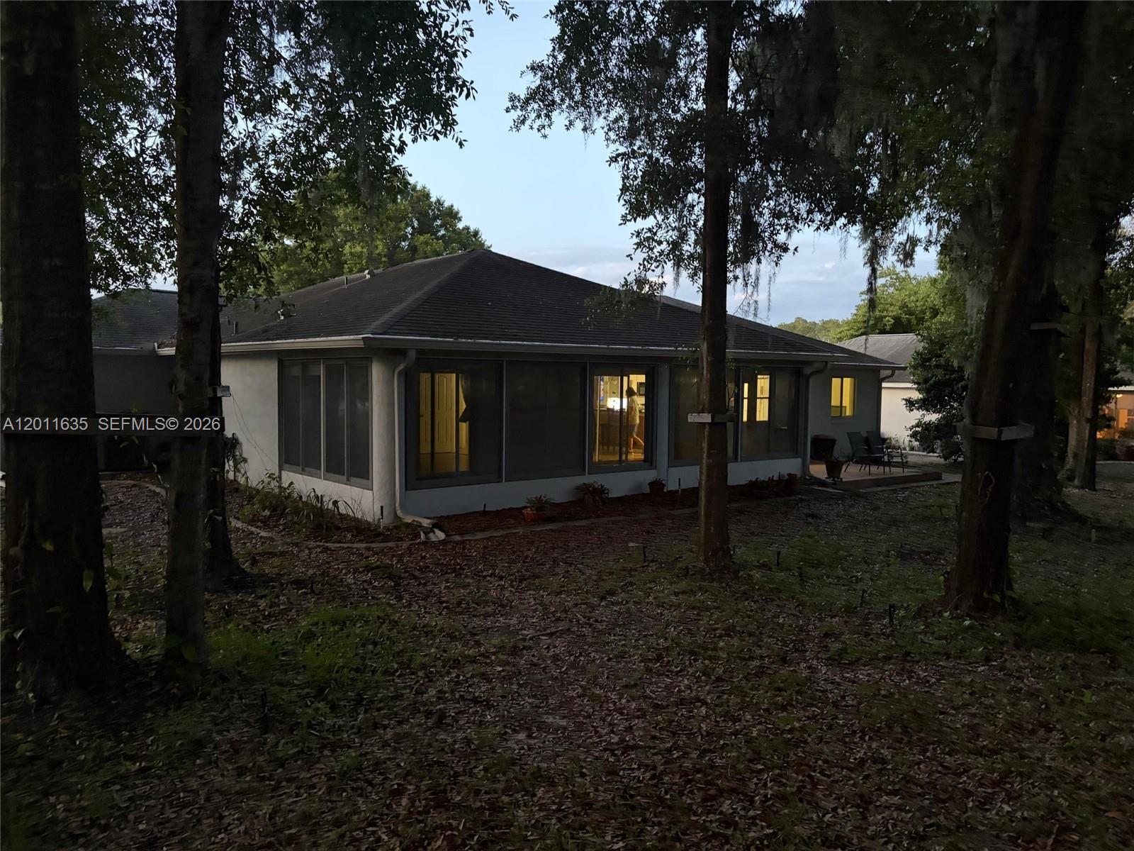 The exterior of a house features a screened-in porch and a small patio area — 6064 SW 103RD LOOP, Ocala FL 34476, OCALA, FL