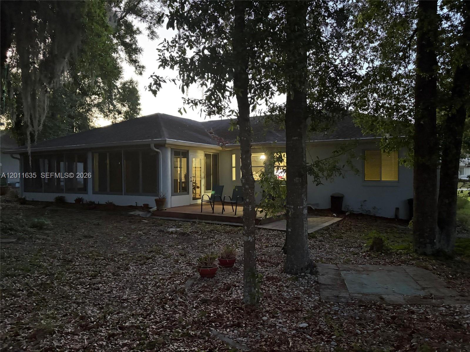 The exterior of a single-story house features a screened-in porch and a small patio — 6064 SW 103RD LOOP, Ocala FL 34476, OCALA, FL