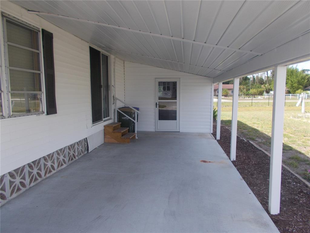A concrete carport with a white metal roof and siding attached to a mobile home — 5154 PALENA BOULEVARD, NORTH PORT, FL