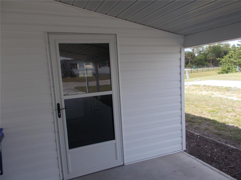A white storm door is installed on the exterior wall of a covered patio — 5154 PALENA BOULEVARD, NORTH PORT, FL