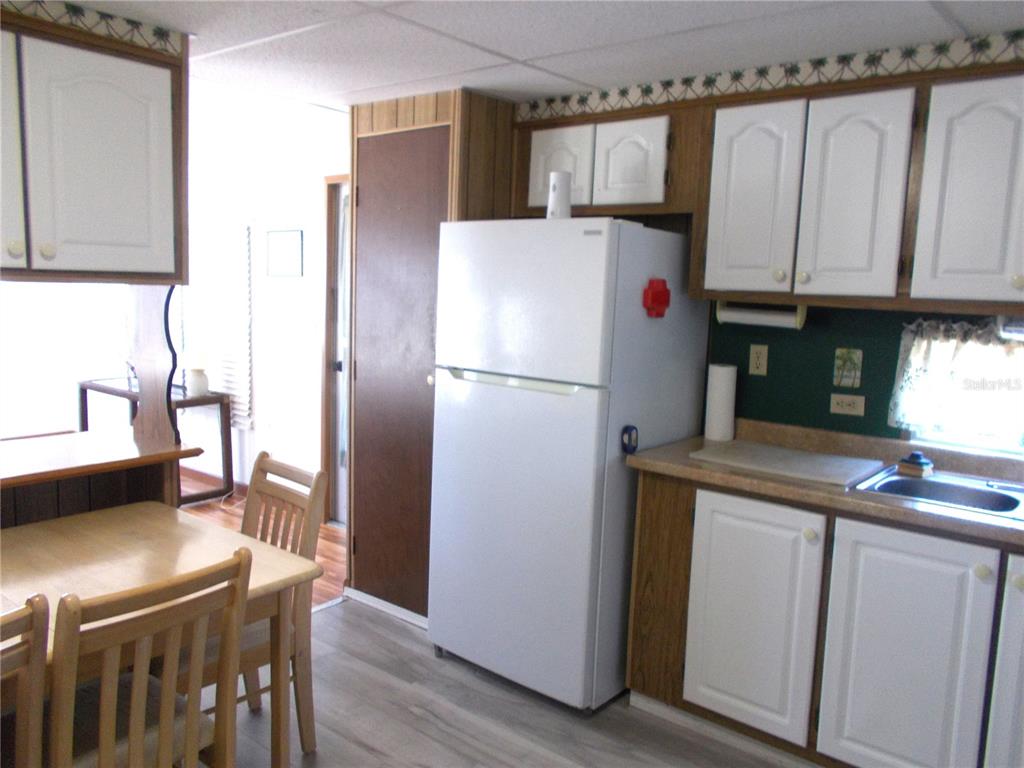 A kitchen features white cabinets, a white refrigerator, wood-look flooring, and a small dining table — 5154 PALENA BOULEVARD, NORTH PORT, FL