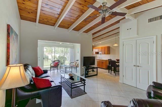 A living room features a vaulted wood-beam ceiling, tile flooring, and an open kitchen view — 6006 MIDNIGHT PASS ROAD UNIT 64, SARASOTA, FL