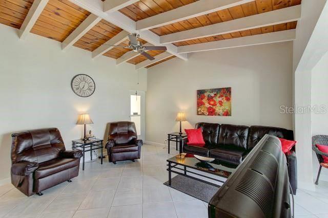 A living room features a vaulted wood-beam ceiling, tile flooring, and brown leather furniture — 6006 MIDNIGHT PASS ROAD UNIT 64, SARASOTA, FL