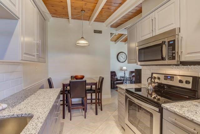 A kitchen with granite countertops, stainless steel appliances, and a dining area with wood ceilings — 6006 MIDNIGHT PASS ROAD UNIT 64, SARASOTA, FL
