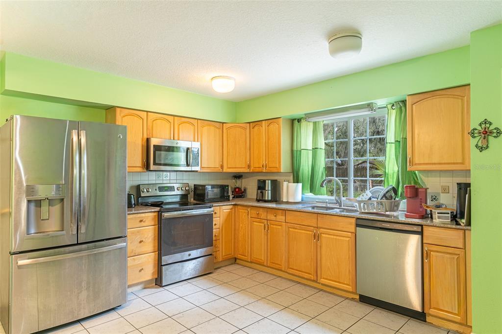 A kitchen with light wood cabinets, stainless steel appliances, and bright green walls — 5103 GREENBROOK LANE, LAKELAND, FL