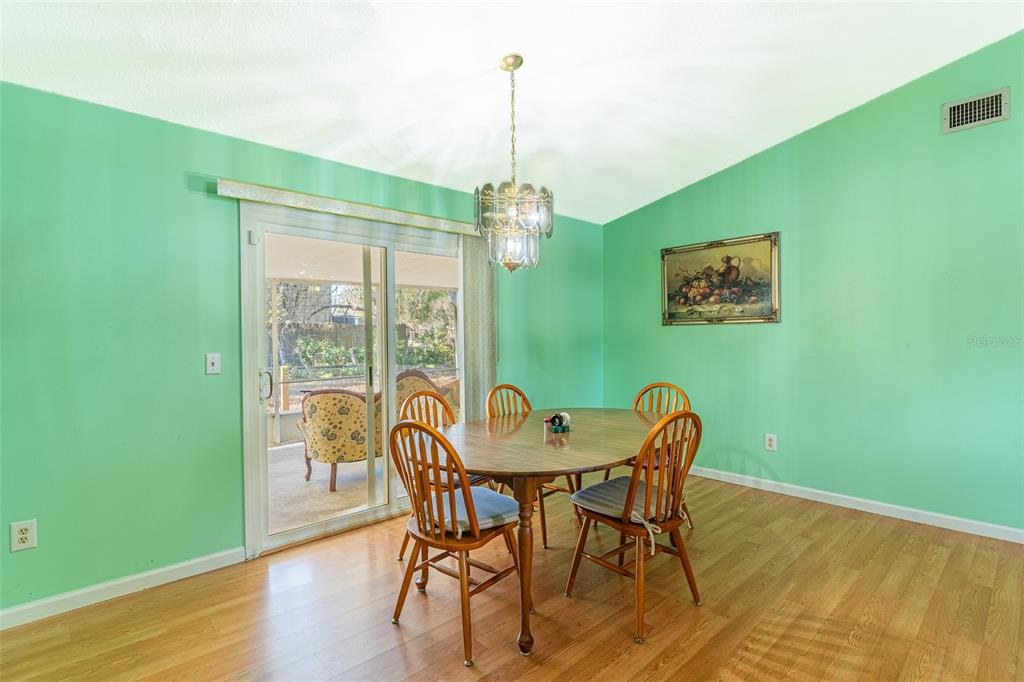 A dining room with mint green walls, wood flooring, a wooden table, and sliding glass doors — 5103 GREENBROOK LANE, LAKELAND, FL