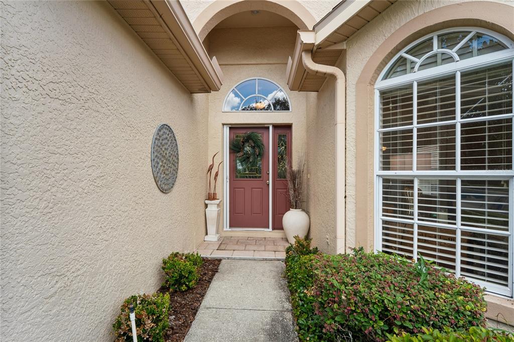 A front entryway features a red door with a wreath, a walkway, and landscaping — 363 QUANE AVENUE, SPRING HILL, FL