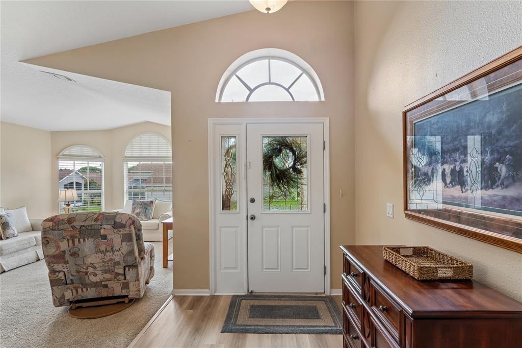 An entryway features a white front door with a sidelight, wood-look flooring, and a dresser — 363 QUANE AVENUE, SPRING HILL, FL