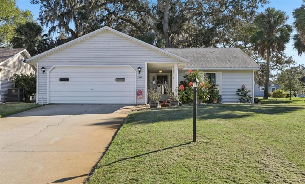 A single-story house with light gray siding, a two-car garage, and a front lawn — 304 BRIGADOON CIRCLE, LEESBURG, FL
