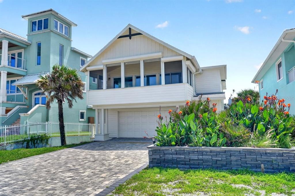 A two-story house with a screened-in porch, a garage, and a stone retaining wall — 6118 S ATLANTIC AVENUE, NEW SMYRNA BEACH, FL