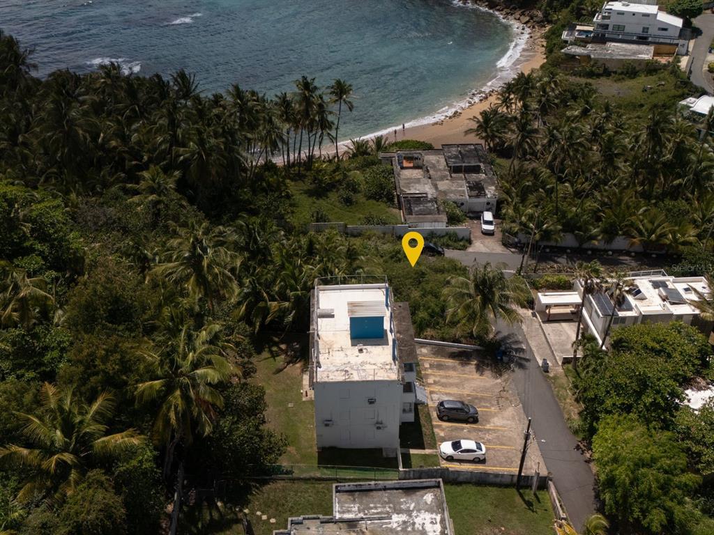 An aerial view shows a white building with a parking lot near a sandy beach — 16 DELFIN CAP DE MAR, VEGA ALTA, PR