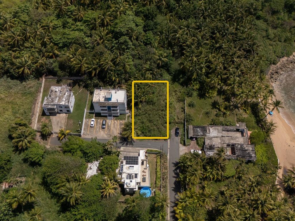 An aerial view shows a rectangular vacant lot outlined in yellow next to coastal buildings — 16 DELFIN CAP DE MAR, VEGA ALTA, PR