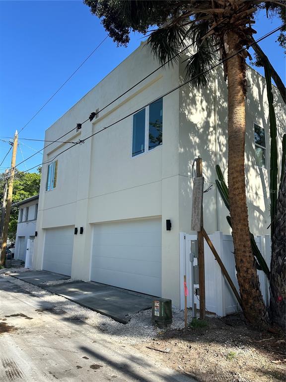 The exterior of a modern, two-story building features two white garage doors and light-colored stucco walls — 2142 5TH AVENUE N, ST PETERSBURG, FL