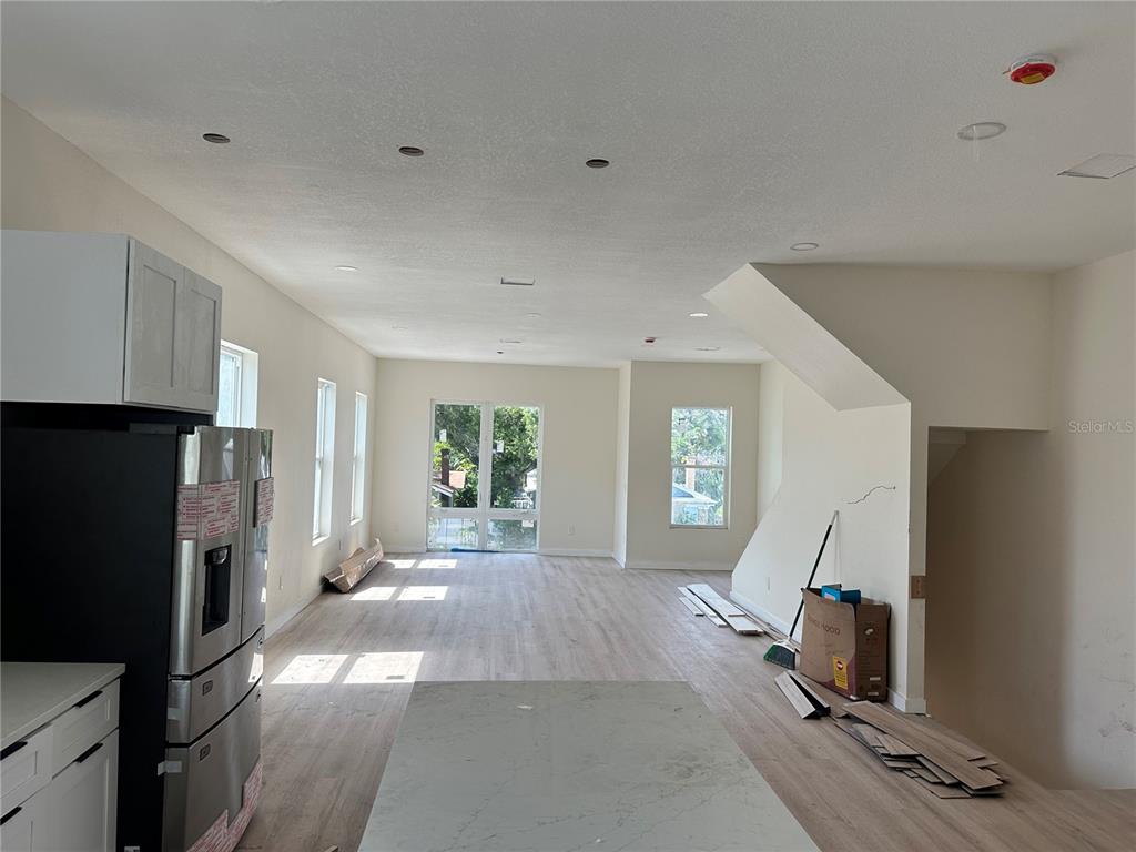 An open-concept kitchen and living area features light wood flooring, white walls, and recessed lighting — 2142 5TH AVENUE N, ST PETERSBURG, FL