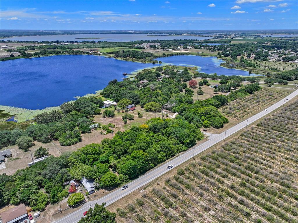 An aerial view shows a road bordering a wooded area, a lake, and agricultural fields — SR-17, HAINES CITY, FL