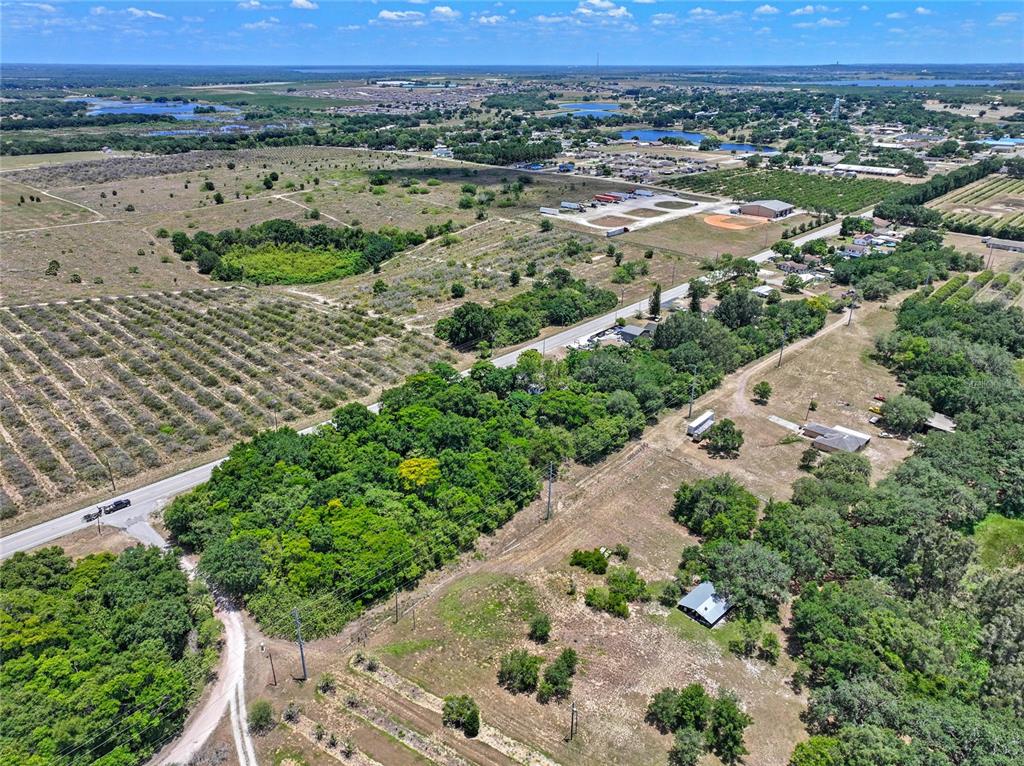 An aerial view shows a rural landscape with agricultural fields, scattered trees, and a small house — SR-17, HAINES CITY, FL