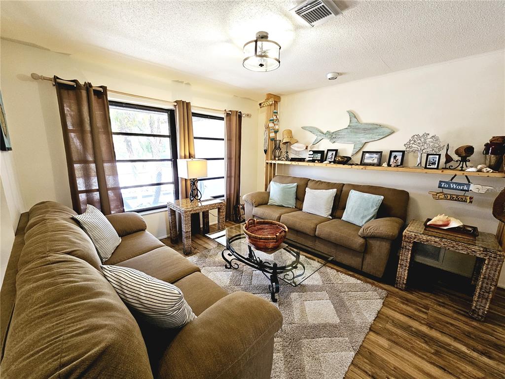 A living room features two brown sofas, a glass coffee table, and coastal wall decor — 2411 BELLE ROAD, ENGLEWOOD, FL