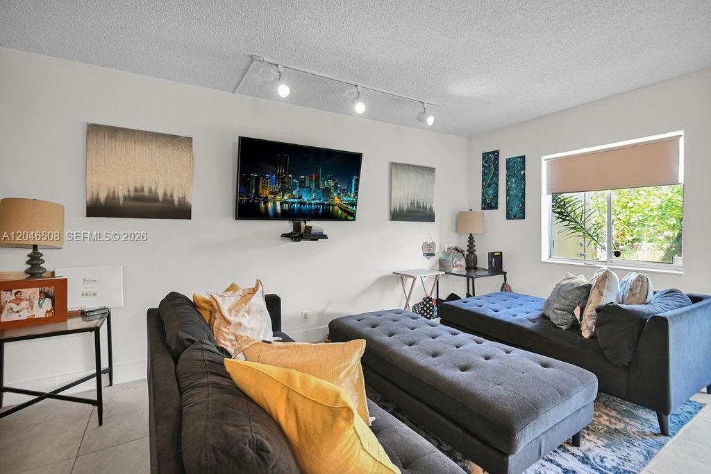 A living room features dark gray sofas, a large television, and track lighting — 7887 NW 7th Ct, Plantation FL 33324, PLANTATION, FL
