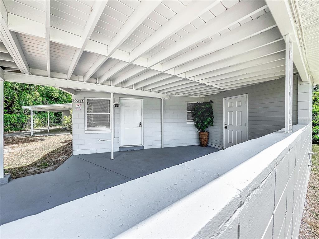 A covered carport area features a concrete floor, white painted walls, and two entry doors — 3025 LONG STREET UNIT A, ORLANDO, FL