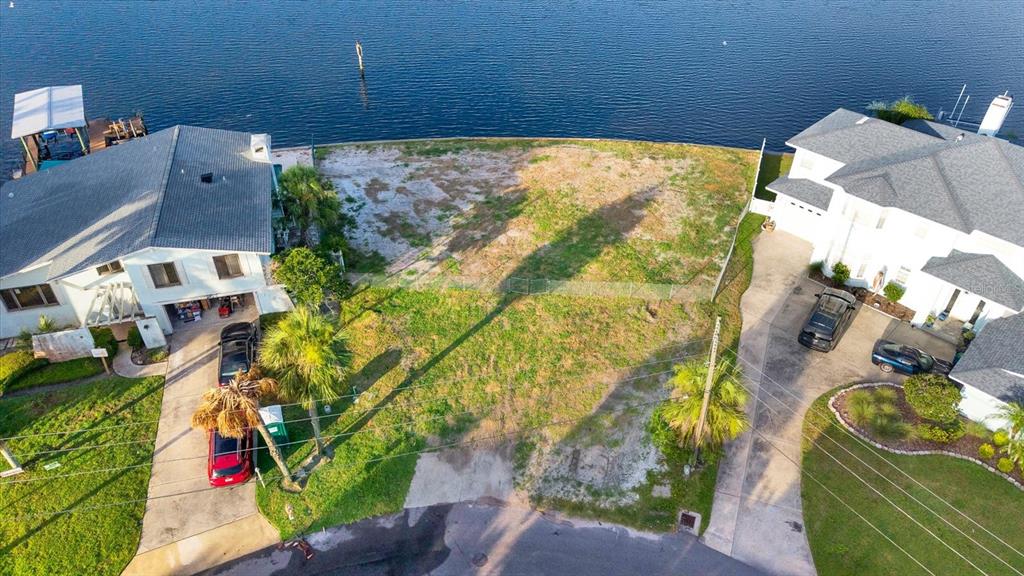 An aerial view shows a vacant waterfront lot situated between two residential houses — 121 AUGUSTA AVENUE, PALM HARBOR, FL